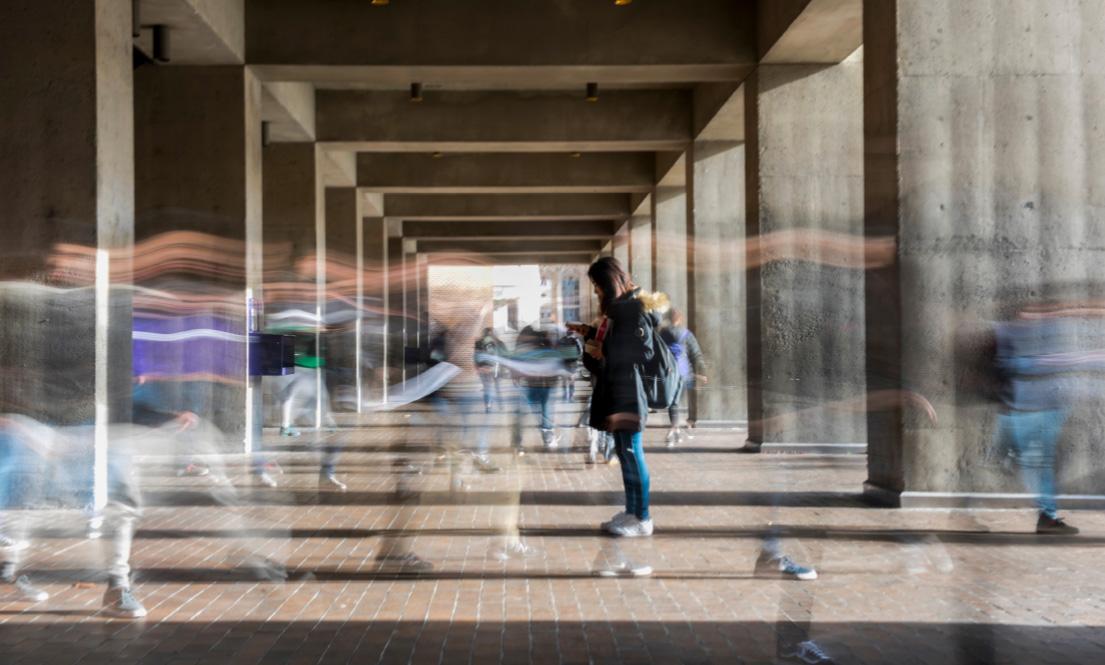 Student standing still while others are moving around them